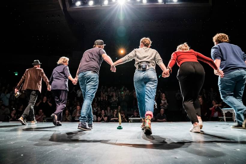 Poetry Slam Performer:innen Hand in Hand beim gemeinsamen Bühnenabgang vor Publikum, Abschlussapplaus eines Auftritts mit Luise Wolff