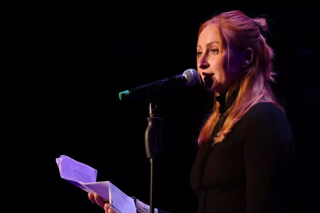Luise Wolff bei einem Poetry Slam Auftritt mit Mikrofon und Textblatt in der Hand, im Scheinwerferlicht auf dunkler Bühne, 2024