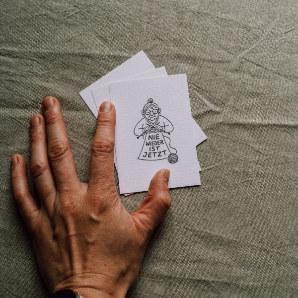 Postkarte – „Nie wieder ist jetzt" (strickende Oma)